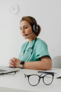 Focused shot of eyeglasses in a teleconsultation setting with a female doctor.